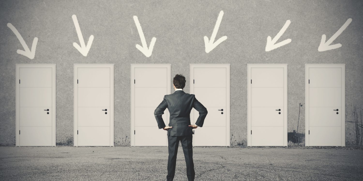 Business person standing in front of doors with arrows over each one.